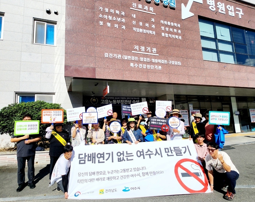 여수시에서 담배연기 없는 환경을 만들기 위한 시위가 진행되고 있으며, 참가자들이 현수막과 피켓을 들고 있다.