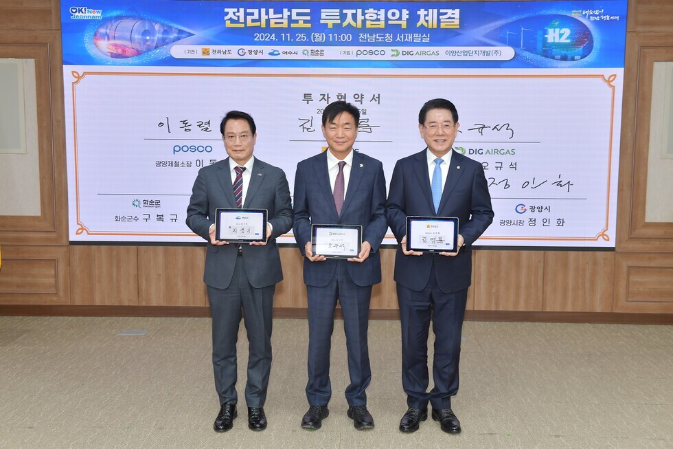 전라남도청에서 투자협약 체결식이 진행되고 있으며, 세 명의 관계자가 협약서를 들고 서 있다.