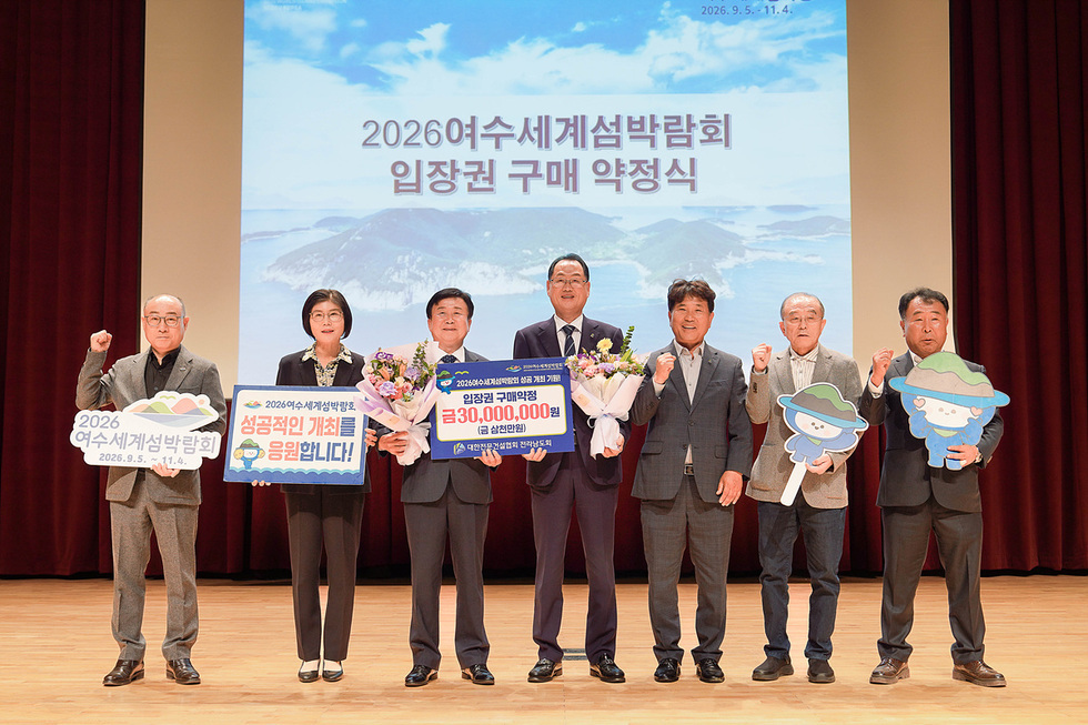 여수문화홀에서 2026여수세계섬박람회 입장권 구매 약정식을 진행하는 모습으로, 참석자들이 입장권 구매 약정식과 성공적인 개최를 기원하는 판넬을 들고 있다.