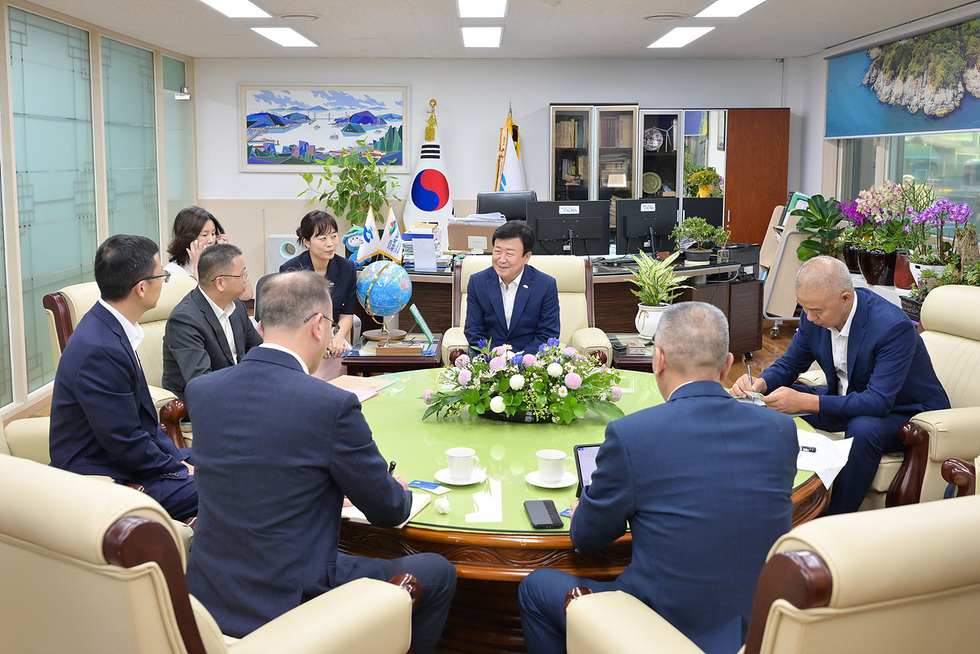 여수시장 정기명이 회의실에서 여러 관계자들과 함께 앉아 대화하고 있는 모습으로, 회의 테이블에는 꽃 장식과 음료가 놓여 있다.