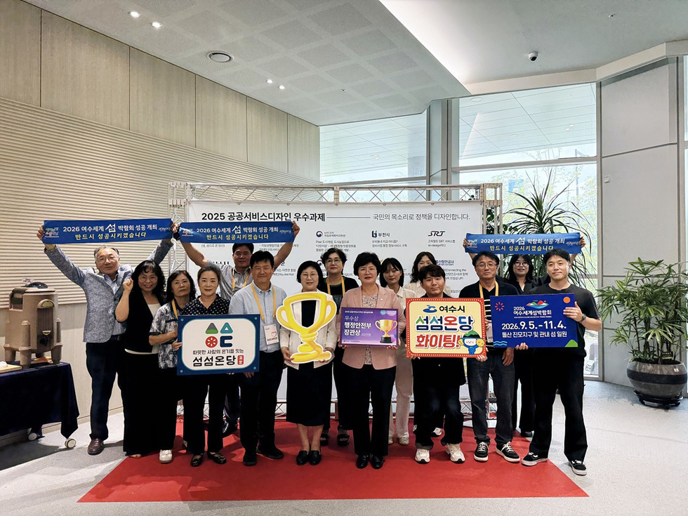여성세계 설 발명대회 참가자들이 상을 들고 기념사진을 찍고 있다. 배경에는 공공서비스디자인 우수과제와 관련된 현수막이 보인다.