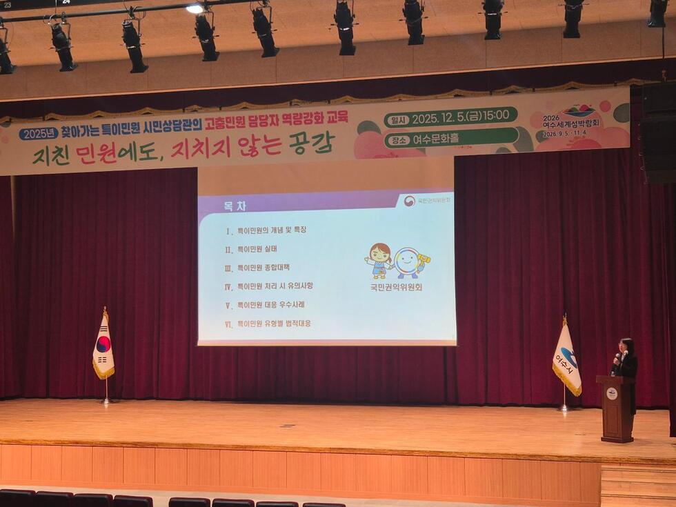 여수문화홀 무대에서 특이민원 대응 역량 강화 교육이 진행되는 모습으로, 강사가 단상에서 발표하고 대형 스크린에 ‘특이민원의 개념 및 특징, 특이민원 실태, 특이민원 종합대책, 특이민원 처리 시 유의사항, 특이민원 대응 우수사례, 특이민원 유형별 법적대응’ 등 목차가 표시되어 있으며, 상단 현수막에는 ‘2025년 찾아가는 특이민원 시민상담관의 고충민원 담당자 역량강화 교육 – 지친 민원에도, 지치지 않는 공감 / 일시 2025년12월5일(금) 15:00 / 장소 여수문화홀’ 문구가 적혀 있다.